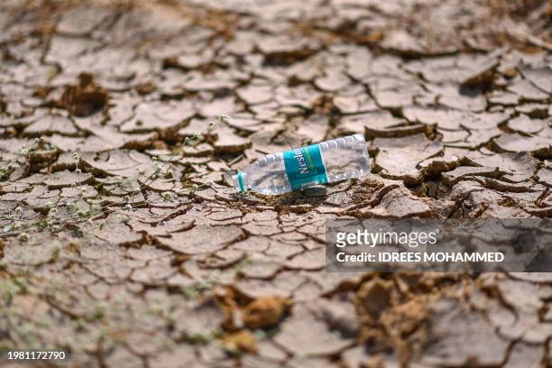 This photograph taken on January 29, 2024 shows an empty plastic water bottle dumped on the arid Doddathogur lakebed in Bengaluru. In the rush to...