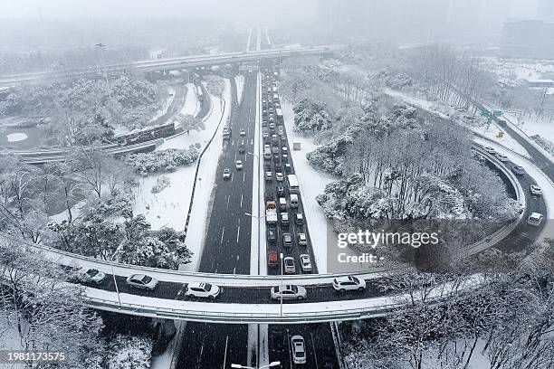 Vehicles make their way amid heavy traffic conditions during snowfall in Wuhan, in central China's Hubei province on February 6, 2024. / China OUT