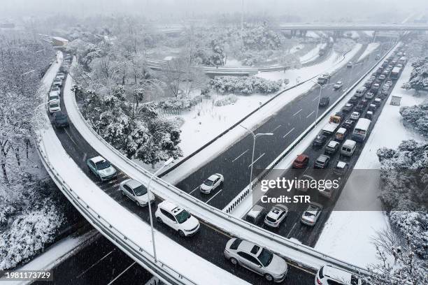 Vehicles make their way amid heavy traffic conditions during snowfall in Wuhan, in central China's Hubei province on February 6, 2024. / China OUT