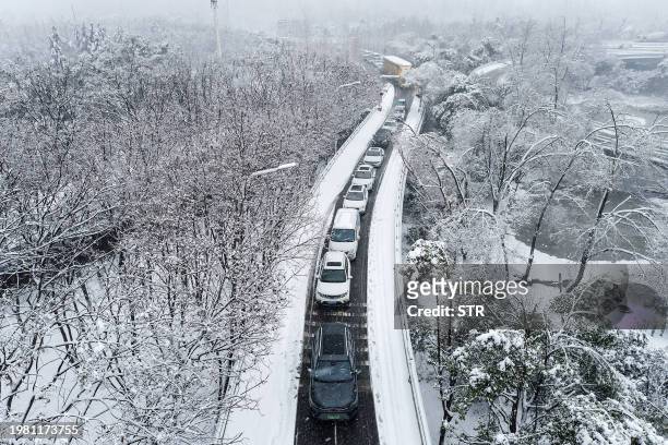 Vehicles make their way amid heavy traffic conditions during snowfall in Wuhan, in central China's Hubei province on February 6, 2024. / China OUT