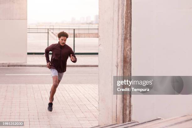 urban determination run: male athlete's intense sprint for improved results - man sprinting stock pictures, royalty-free photos & images