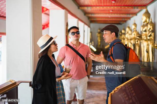 private tourist guide explaining the place history to group traveler exploring the grand palace in bangkok - indian tour guide stock pictures, royalty-free photos & images