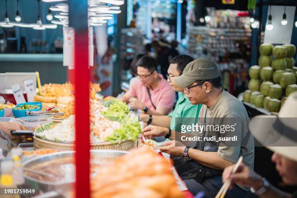asian traveler buy thai style halal barbecue stick food from street vendor - halal stock pictures, royalty-free photos & images