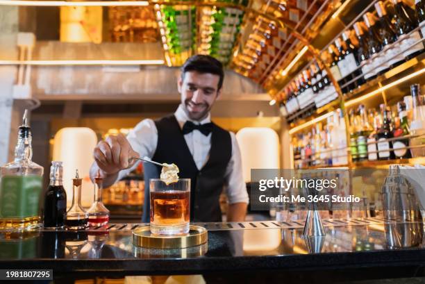 male bartender serve drinks to customers at the bar counter - bartender stock pictures, royalty-free photos & images