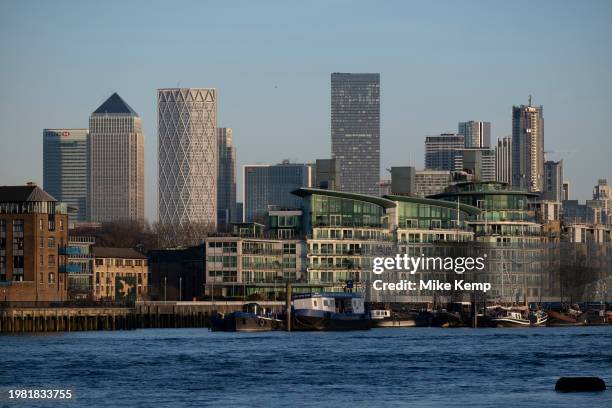 Residential flats and riverside apartment buildings along the River Thames at Wapping looking towards the skyscrapers of Canary Wharf financial...