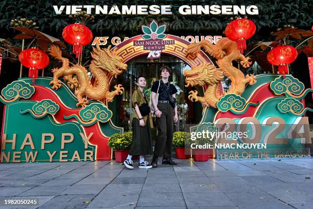 Couple poses for photo in front of a dragon-shaped installation in Hanoi on February 6 as Vietnamese prepare to celebrate their traditional Tet or...