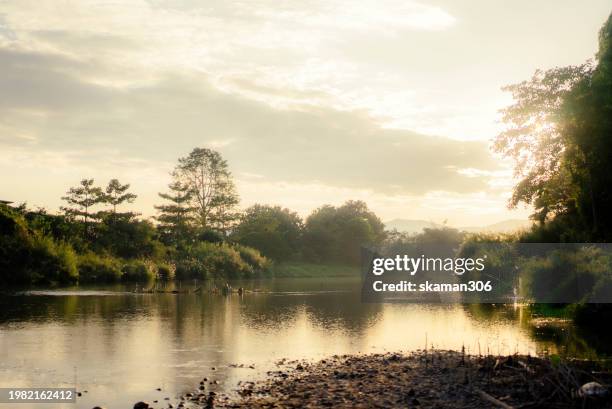 the sun sets over a tranquil river landscape, with gentle waters reflecting the golden light of the early evening. - 岩手山 ストックフォトと画像