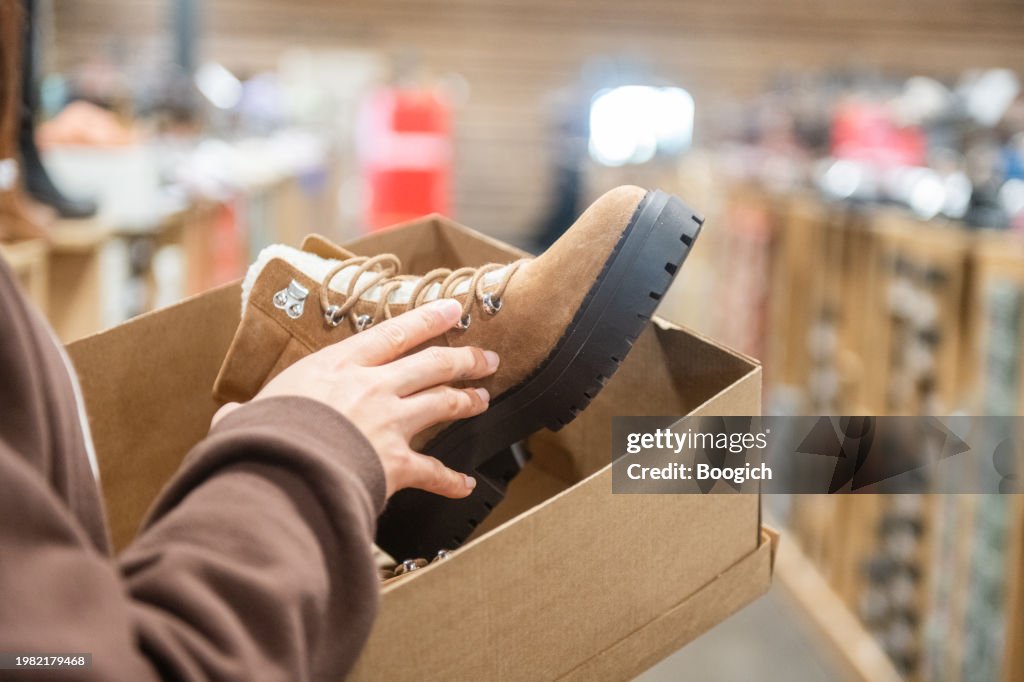 Mano de mujer sosteniendo botas para la venta