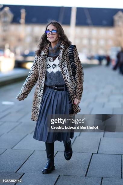 Guest wears sunglasses, a brown leopard print fluffy jacket , a a gray wool turtleneck pullover , a leather belt, a midi pleated skirt , black...