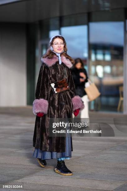 Guest wears glasses, a blue balaclava, a brown fluffy fur coat wuth fluffy purple cuffs and collar, a gray pleated skirt, black leather shoes,...