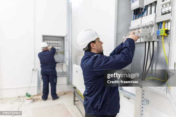 two male electricians working in an electrical system control cabinet - distribution board stock pictures, royalty-free photos & images