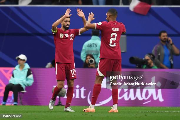 Hassan Al-Haydos and Pedro Miguel of Qatar celebrate their team's first goal, an own goal scored by Utkir Yusupov of Uzbekistan during the AFC Asian...