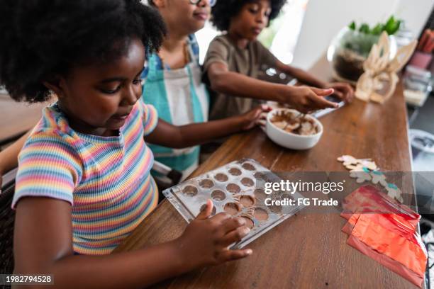 girl making easter eggs with her family at home - wrapped chocolate stock pictures, royalty-free photos & images