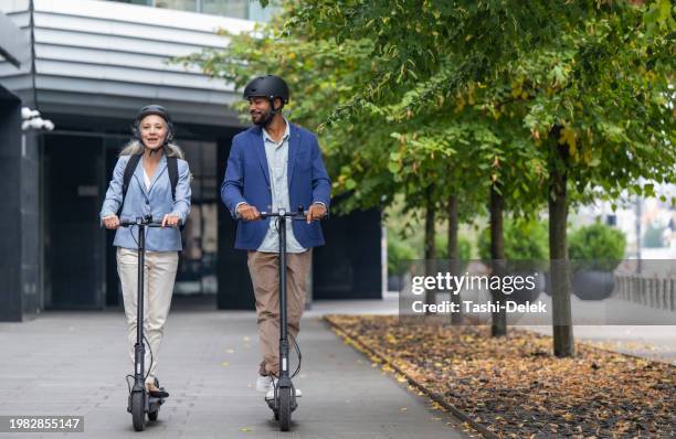 smiling couple riding electric scooter - push scooter stock pictures, royalty-free photos & images