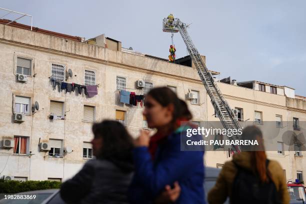 Residents wait outside as firefighters inspect a building from a ladder while emergency services are looking for potential victims after a habitation...