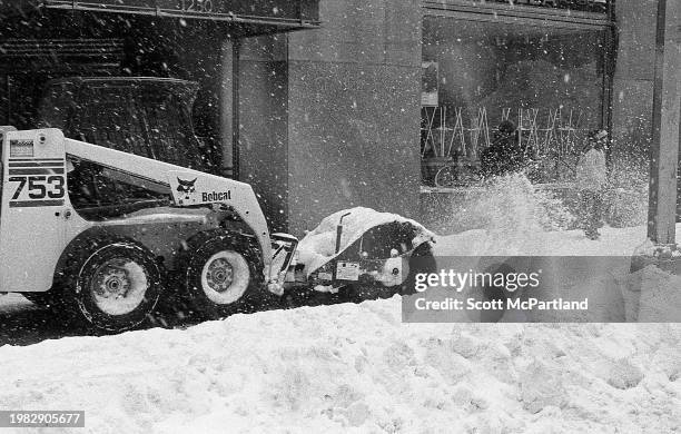 View of a snow sweeper clearing snow from the sidewalk on 6th Avenue during the President's Day blizzard, New York, New York, February 17, 2003.