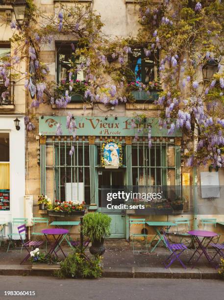 parisian charm: wisteria-adorned café terrace on a cosy spring street" - paris island stock pictures, royalty-free photos & images