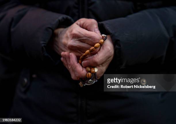 Woman holding rosary beads recites a prayer with anti-abortion activists near the Planned Parenthood clinic where they are confronted by abortion...