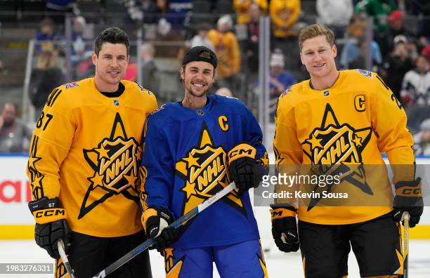 Sidney Crosby of the Pittsburgh Penguins, Justin Bieber and Nathan MacKinnon of the Colorado Avalanche pose for a group photo during warm-up before...