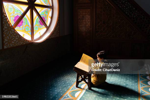 boy sitting in mosque reading quran - bookstand stock pictures, royalty-free photos & images