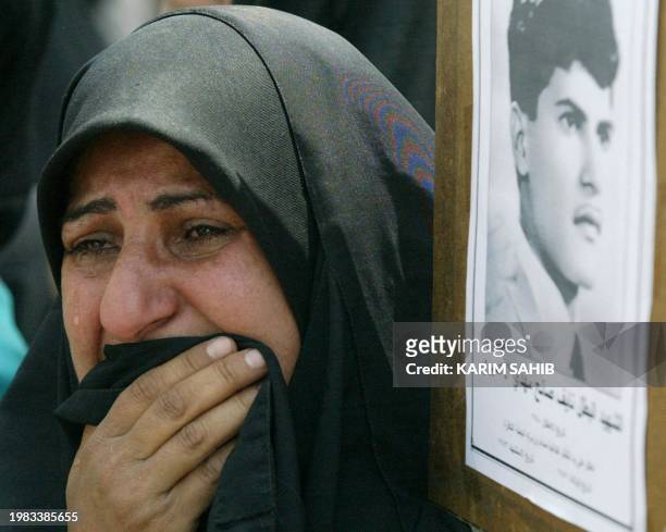 Woman cries 11 May 2003 as she carries the picture of her dead son Naif Saleh Mehdi during a rally in Baghdad to commemorate the victims of the...