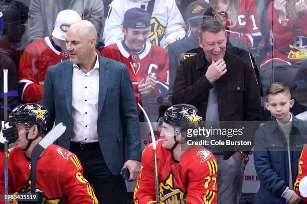 Head coach Rick Tocchet of the Vancouver Canucks shares a laugh with NHL Hall of Fame Player Wayne Gretzky during the game between Team Matthews and...