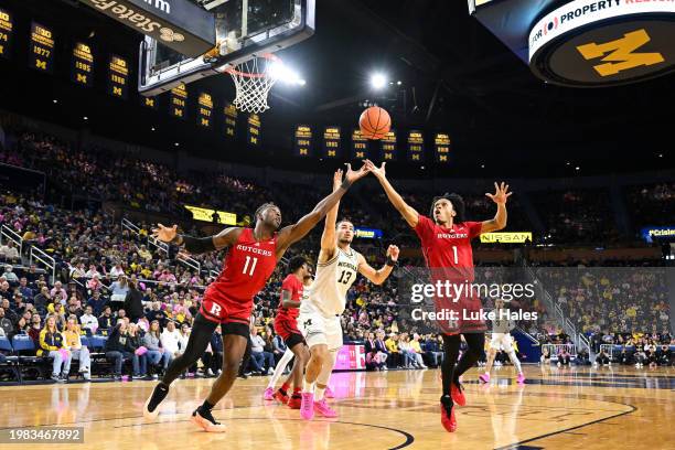 Clifford Omoruyi of the Rutgers Scarlet Knights, Olivier Nkamhoua of the Michigan Wolverines, and Jamichael Davis battle for a rebound during the...