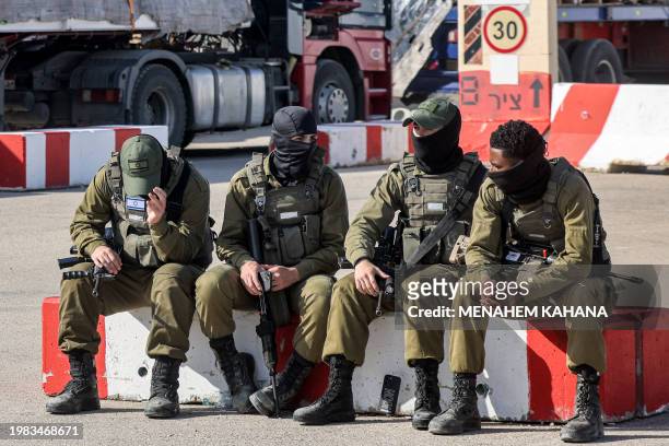 Israeli army soldiers sit together near one of the Egyptian trucks bringing in humanitarian aid supplies to the Gaza Strip, on the Israeli side of...