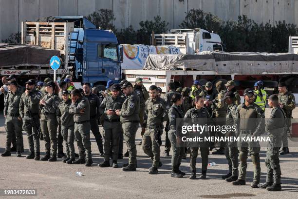 Israeli border guards stand guard near the Egyptian trucks bringing in humanitarian aid supplies to the Gaza Strip, on the Israeli side of the Kerem...