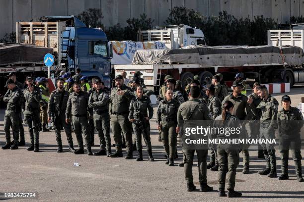 Israeli border guards stand guard near the Egyptian trucks bringing in humanitarian aid supplies to the Gaza Strip, on the Israeli side of the Kerem...