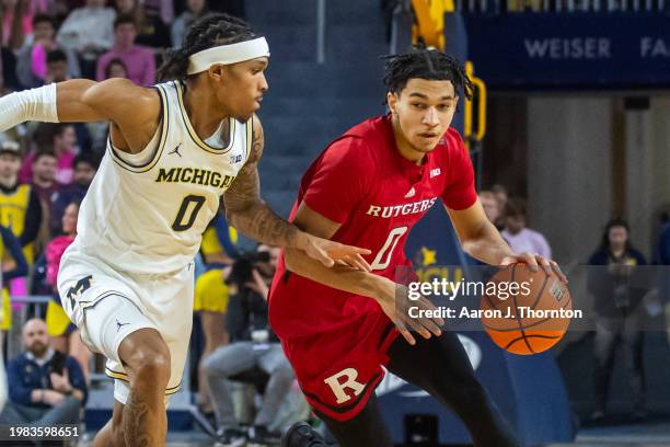 Derek Simpson of the Rutgers Scarlet Knights dribbles the ball against Dug McDaniel of the Michigan Wolverines during the first half of a college...