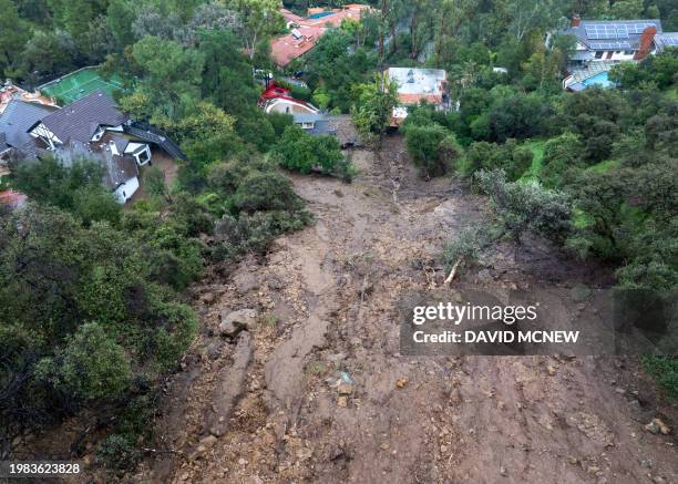 In an aerial view, a mudslide leads to a home where it smashed through its garage as a historic atmospheric river storm inundates the Studio City...