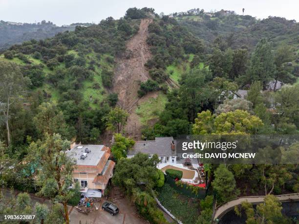 In an aerial view, a mudslide leads to a home where it smashed through its garage as a historic atmospheric river storm inundates the Studio City...