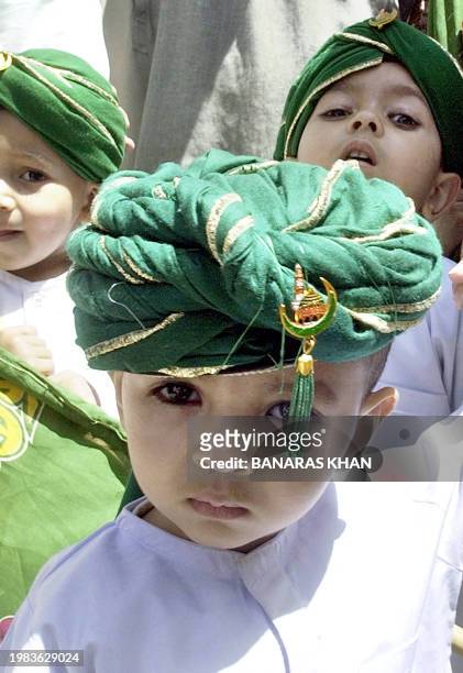 Pakistani Muslim children wear green turbans as they take part along with other devotees during a religious march to celebrate the birthday of...