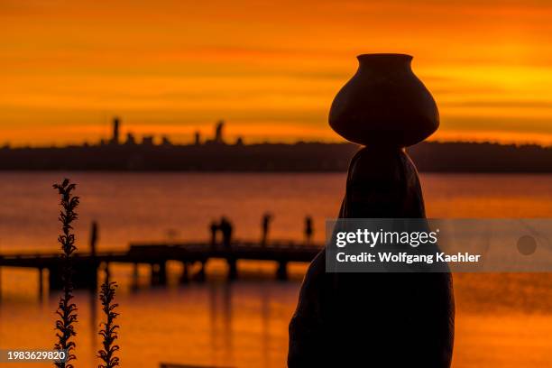 Bronze statue of a water bearer by Glenna Goodacre silhouetted at sunset at the David E. Brink Park on Lake Washington in Kirkland, Washington State,...