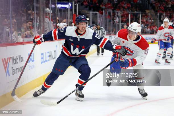 Dylan Strome of the Washington Capitals and Kaiden Guhle of the Montreal Canadiens battle for a puck during a game at Capital One Arena on February...