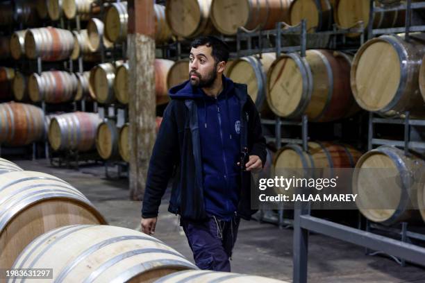 Worker in Dalton Winery walks past wine barrels in the northern Israeli of Moshav of Dalton near the Lebanon border on January 29, 2024. Black clouds...