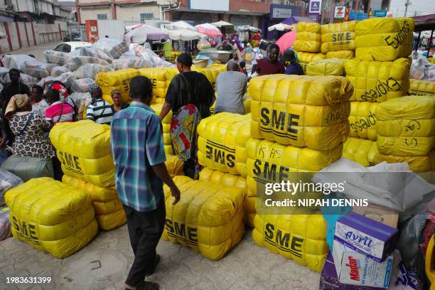 People walk between bales of secondhand clothes at the Kantamanto market in Accra, Ghana, on November 15, 2023. Kantamanto market is vast, spanning...