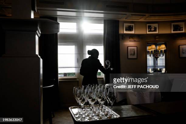 An employee examines a glass in a room of the Auberge de Collonges restaurant, in Collonges au Mont d'Or on January 26, 2024. The renovated inn,...