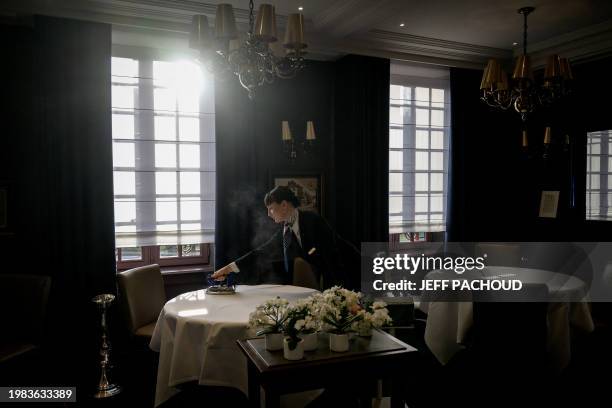 An employee irons the cloth of a table as she prepares a room of the Auberge de Collonges restaurant, in Collonges au Mont d'Or on January 26, 2024....