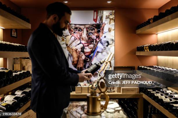 Wine steward examines a bottle in the cellar of the Auberge de Collonges restaurant, in Collonges au Mont d'Or on January 26, 2024. The renovated...