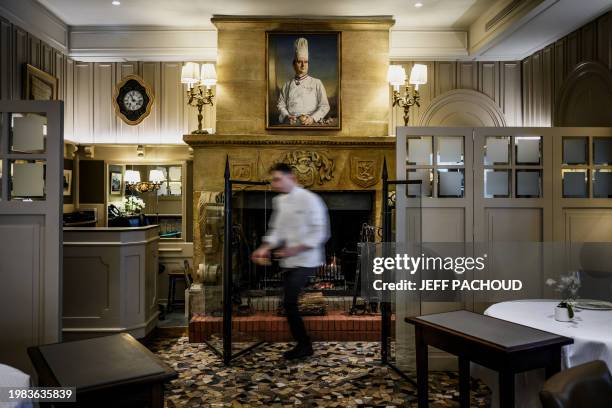 Cook passes by a portrait of Paul Bocuse at the Auberge de Collonges restaurant, in Collonges au Mont d'Or, on January 26, 2024. The renovated inn,...