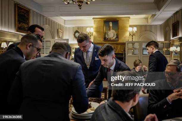 Waiters work during lunch service next to clients and next to a portrait of Paul Bocuse at the Auberge de Collonges restaurant, in Collonges au Mont...