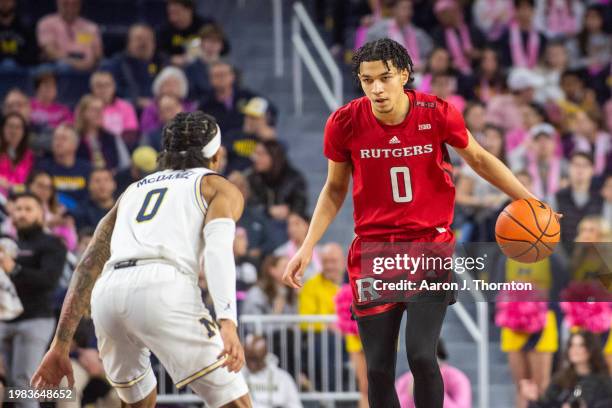 Derek Simpson of the Rutgers Scarlet Knights dribbles the ball against Dug McDaniel of the Michigan Wolverines during the first half of a college...