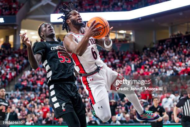 Joe Toussaint of the Texas Tech Red Raiders twists in the air as he attempts a layup against Aziz Bandaogo of the Cincinnati Bearcats during the...