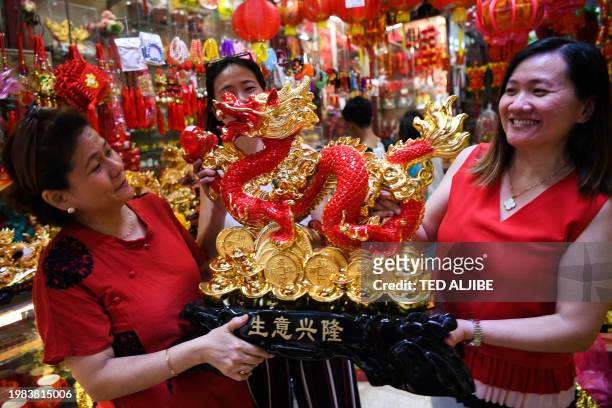 Store owners show a wooden dragon statue at a shop in the Chinatown district of Manila on February 7 ahead of the Lunar New Year of the Dragon which...