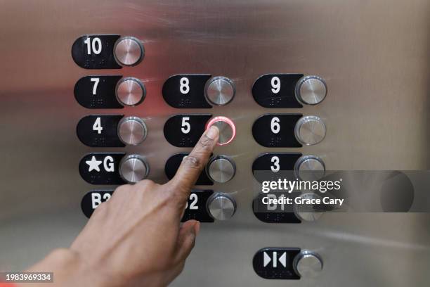 woman presses button in elevator - ascensor fotografías e imágenes de stock