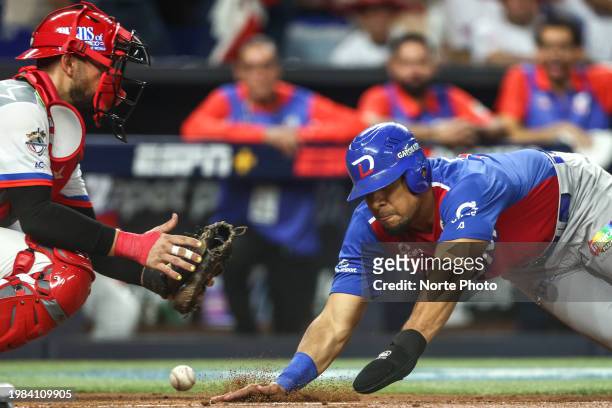 Ramon Hernández of Tigres del Licey of Dominican slides safely at home plate with catcher Jonathan Morales of Criollos de Caguas of Puerto Rico in...