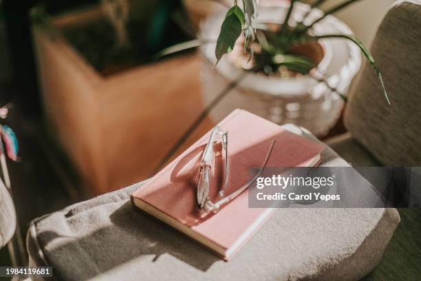 reading glasses and book on sofa, casting shadows - occhiali da lettura foto e immagini stock