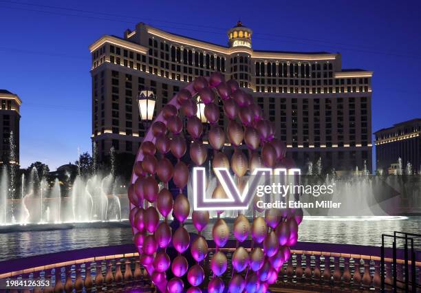 The Fountains of Bellagio launch behind a display of footballs with a Super Bowl LVIII logo on the CBS Sports set being built for the game in front...